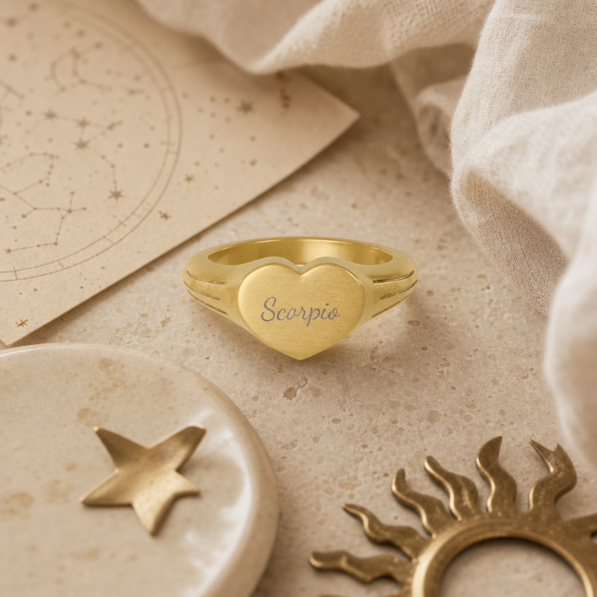 Scorpio zodiac heart signet ring celestial flatlay — zodiac chart and brass star with engraved Scorpio heart signet, astrology gift styling
