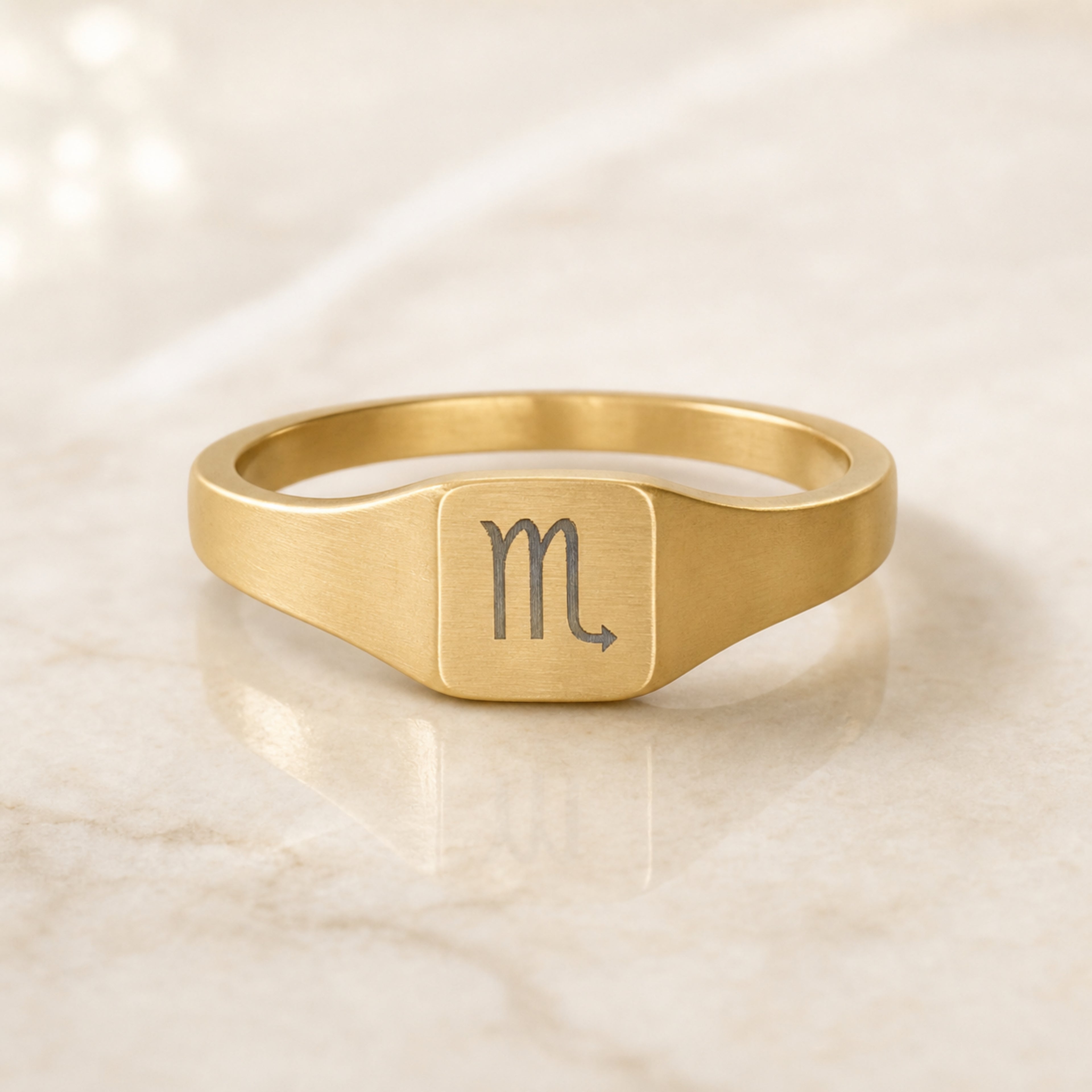 Scorpio zodiac square signet ring linen flatlay — engraved Scorpion ring on rumpled cream linen, editorial product shot