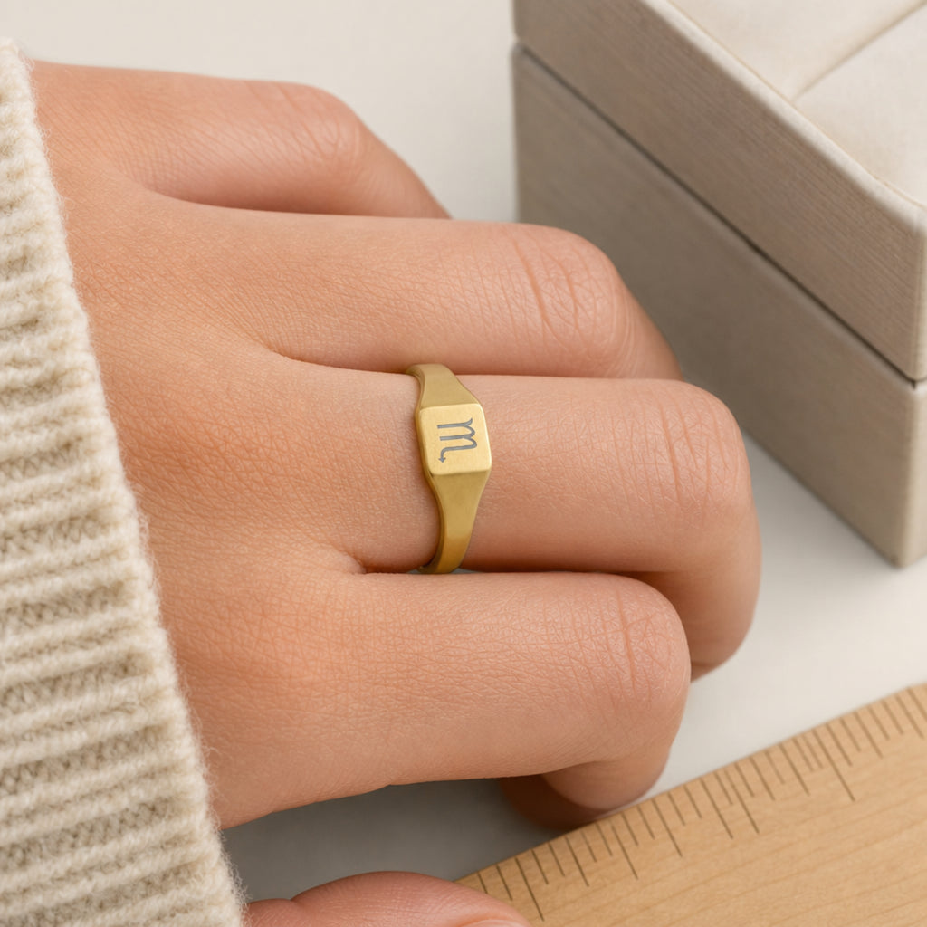 Scorpio zodiac square signet ring scale-in-hand — fingers holding ring next to gift box and ruler, dainty 20mm signet sizing