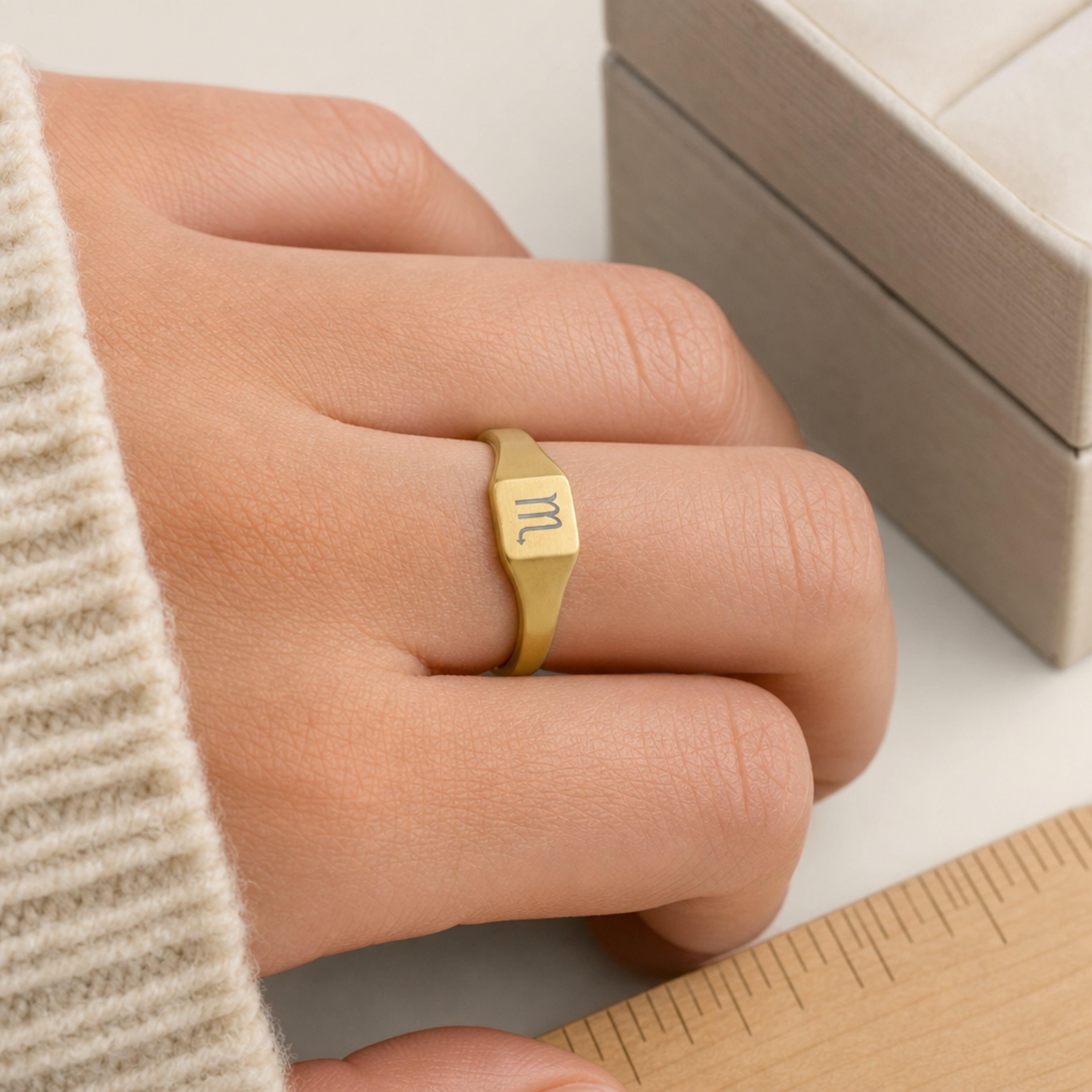 Scorpio zodiac square signet ring scale-in-hand — fingers holding ring next to gift box and ruler, dainty 20mm signet sizing