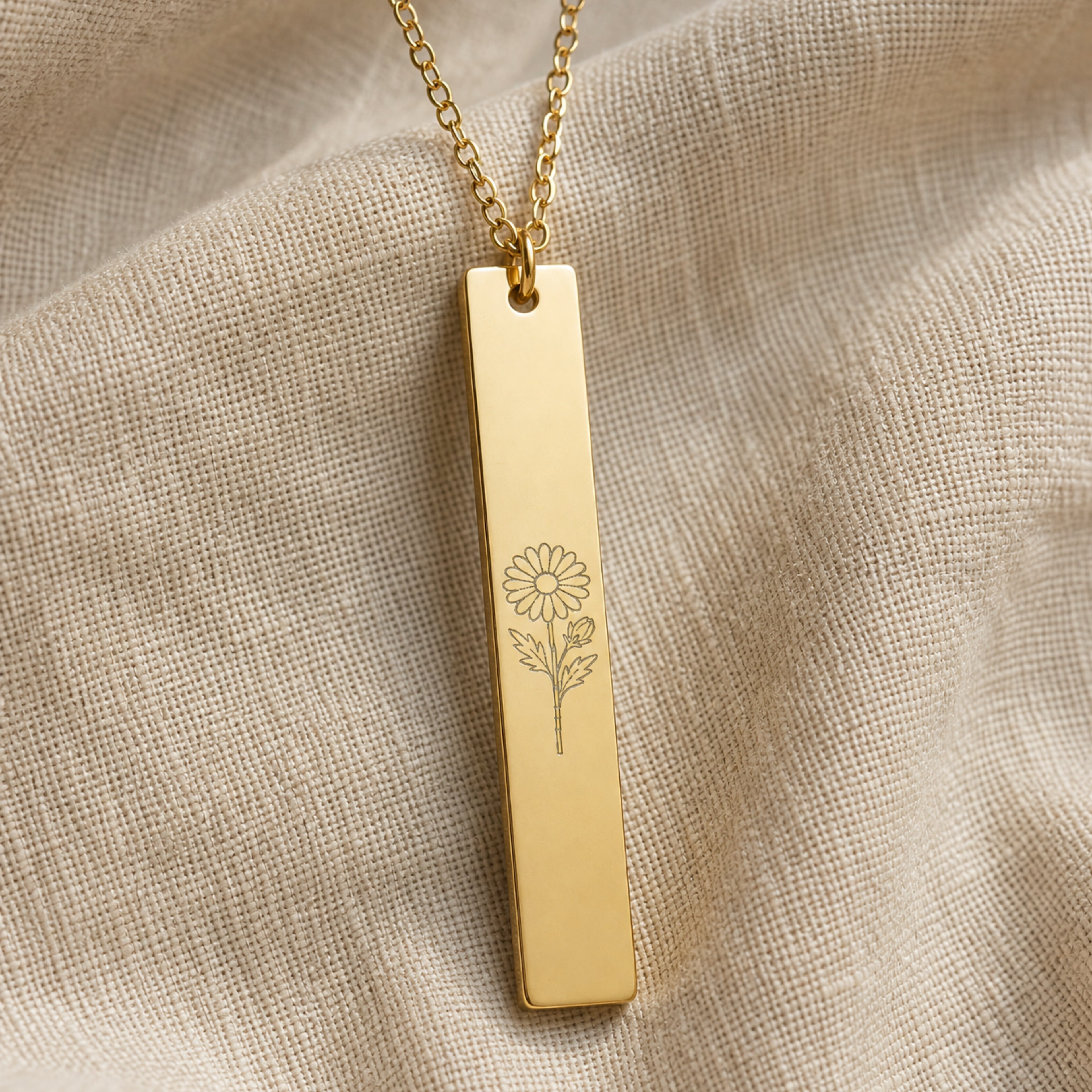 September birth flower necklace — Aster engraved vertical bar pendant flatlay with dried botanicals on cream linen