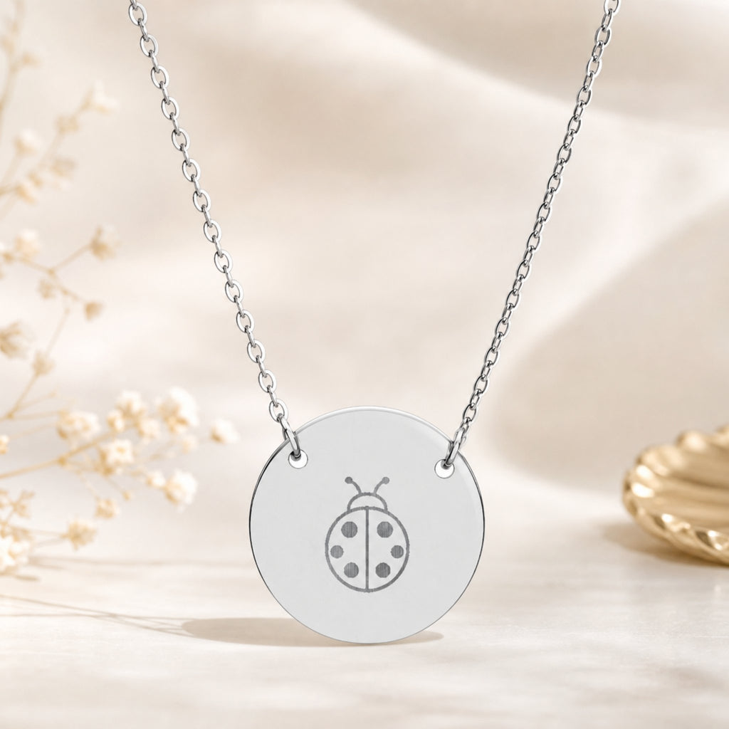 Dainty engraved ladybug coin necklace in stainless steel — laser-engraved ladybug on polished round pendant, clean editorial styling