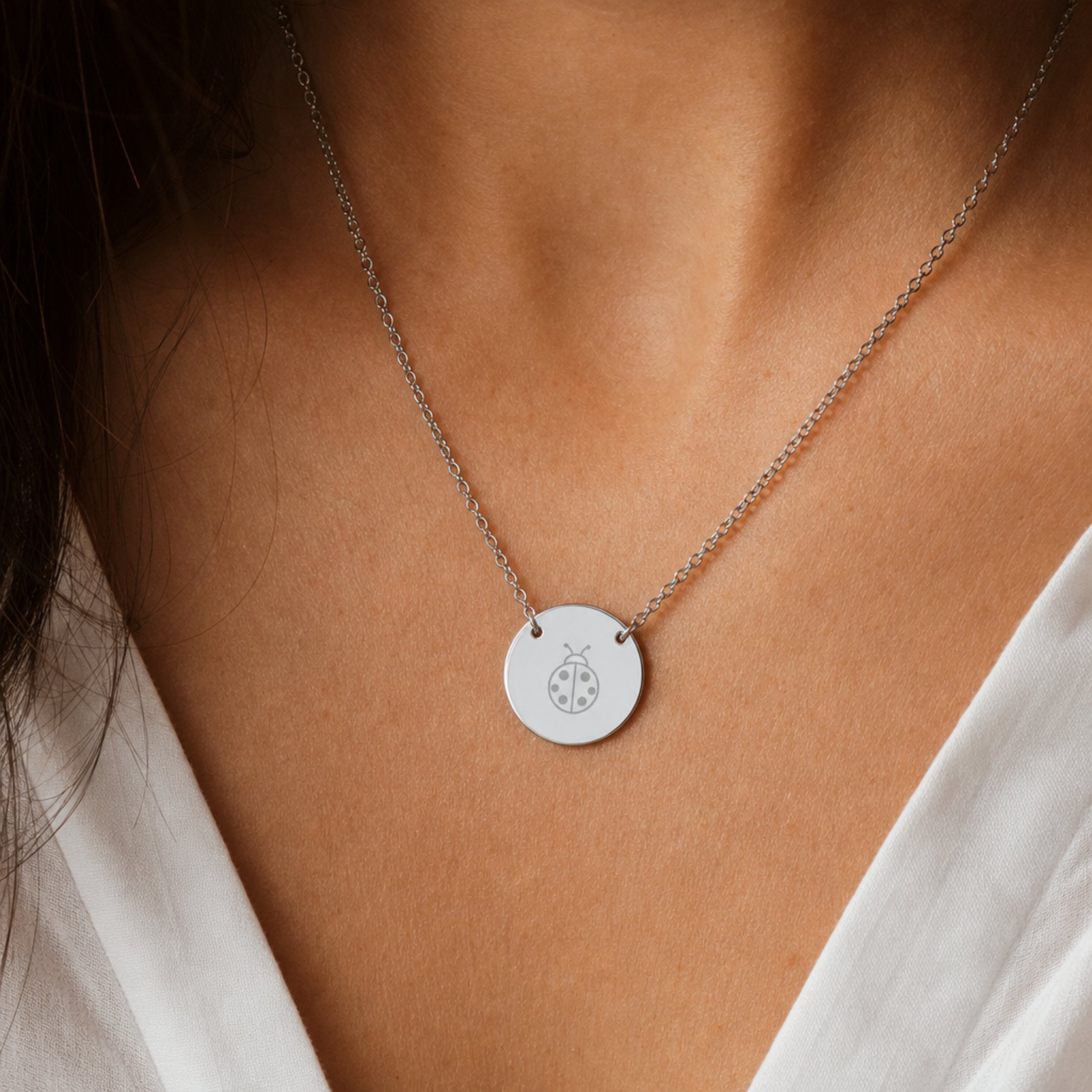 Dainty engraved ladybug coin necklace in stainless steel — laser-engraved ladybug on polished round pendant, clean editorial styling