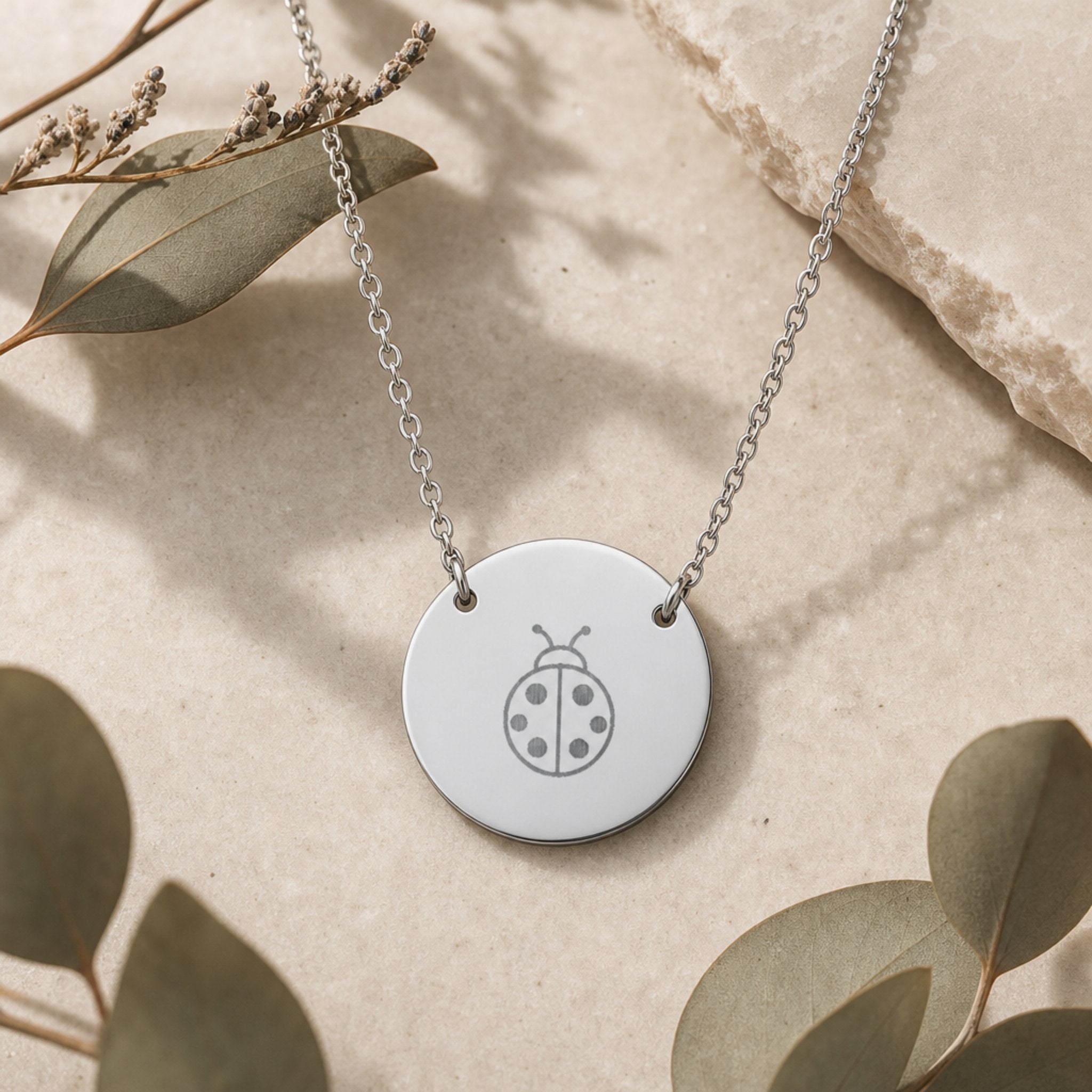 Dainty engraved ladybug coin necklace in stainless steel — laser-engraved ladybug on polished round pendant, clean editorial styling