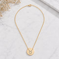 Taurus zodiac coin necklace marble flatlay — 18K gold pendant engraved with Taurus Bull star sign on white marble with dried floral, premium personalized astrology necklace gift for May birthday, Taurusian present