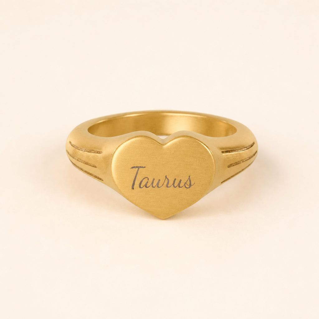 Taurus zodiac heart signet ring studio front — clean cream backdrop product shot, 18K gold matte PVD