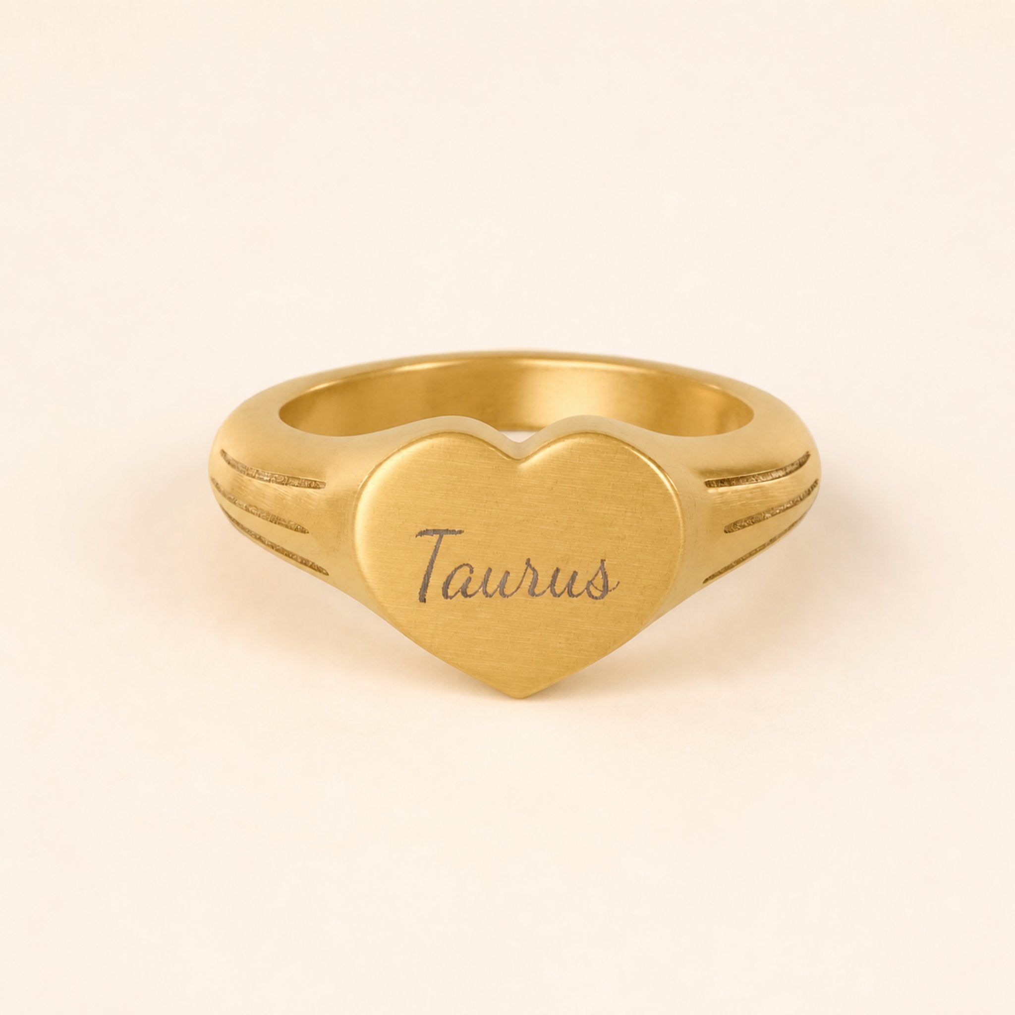 Taurus zodiac heart signet ring studio front — clean cream backdrop product shot, 18K gold matte PVD
