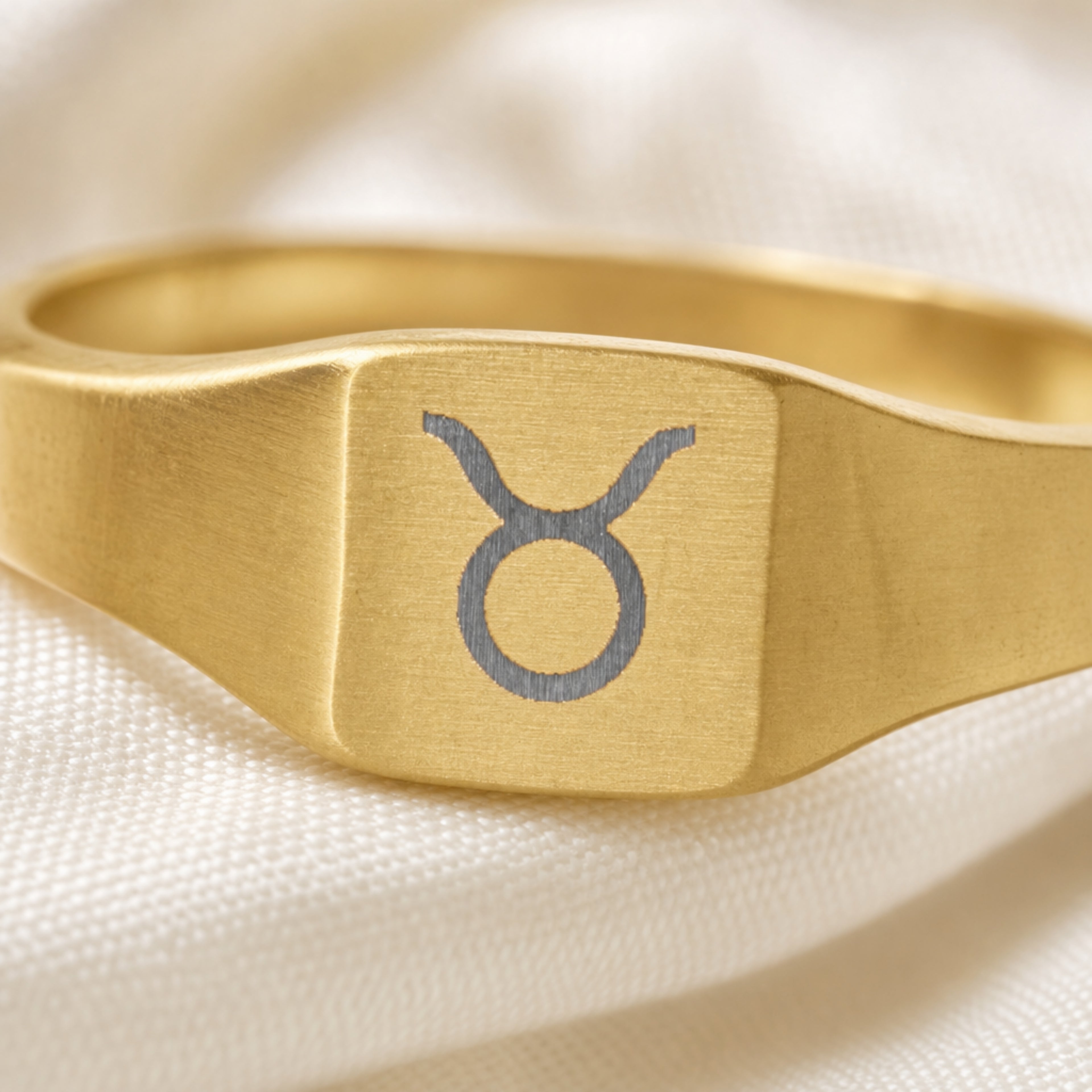 Taurus zodiac square signet ring engraving close-up — laser-etched Bull detail, brushed grey on matte gold