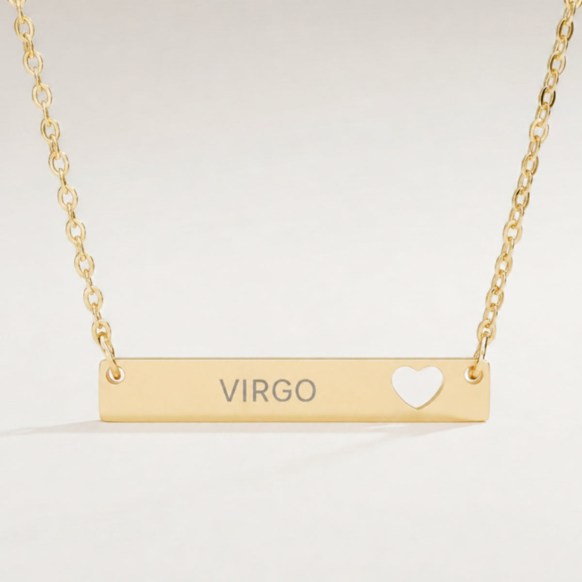Virgo zodiac necklace close-up — 18K Gold polished cutout heart bar pendant with grey laser-etched VIRGO, see-through heart cutout, premium macro on clean background