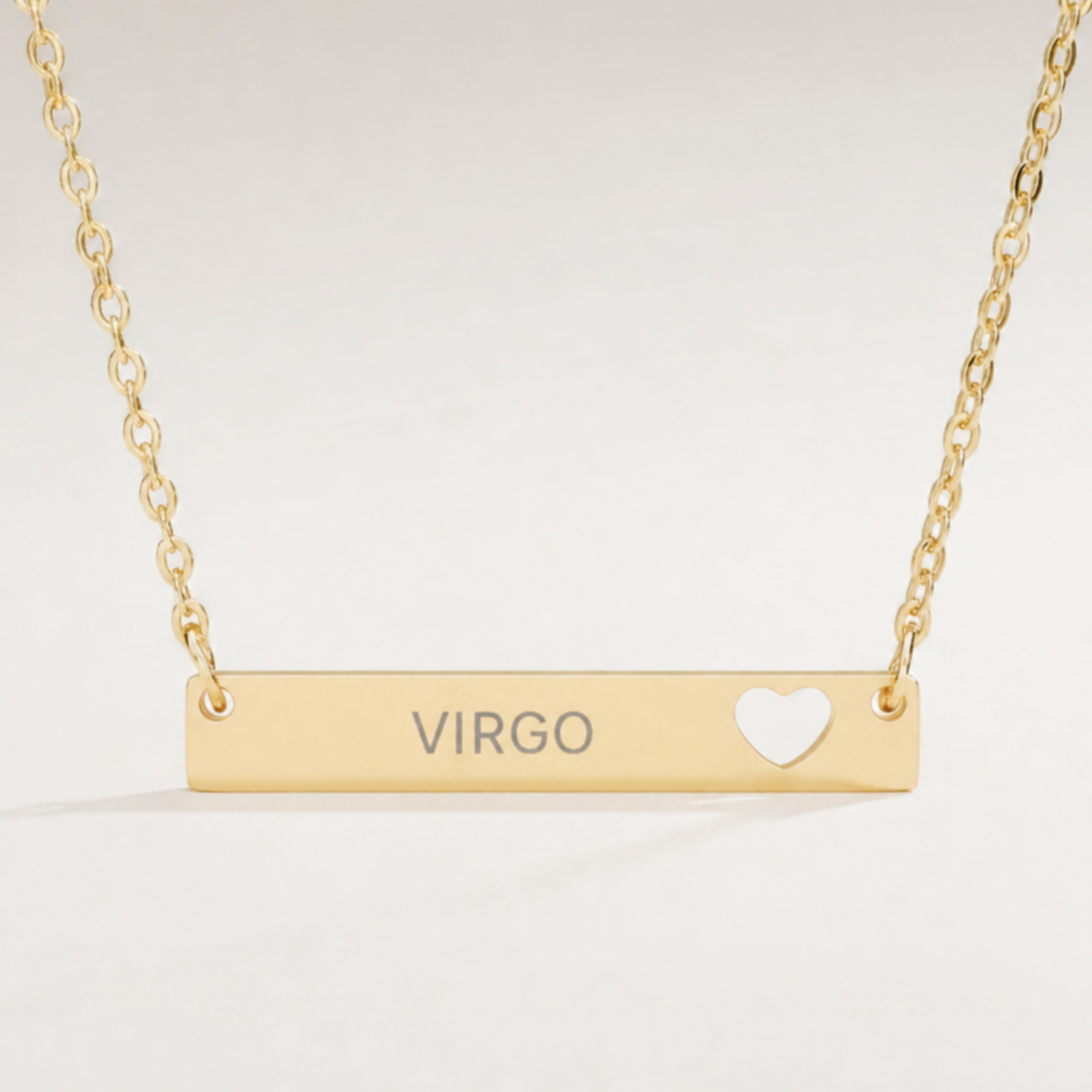 Virgo zodiac necklace close-up — 18K Gold polished cutout heart bar pendant with grey laser-etched VIRGO, see-through heart cutout, premium macro on clean background