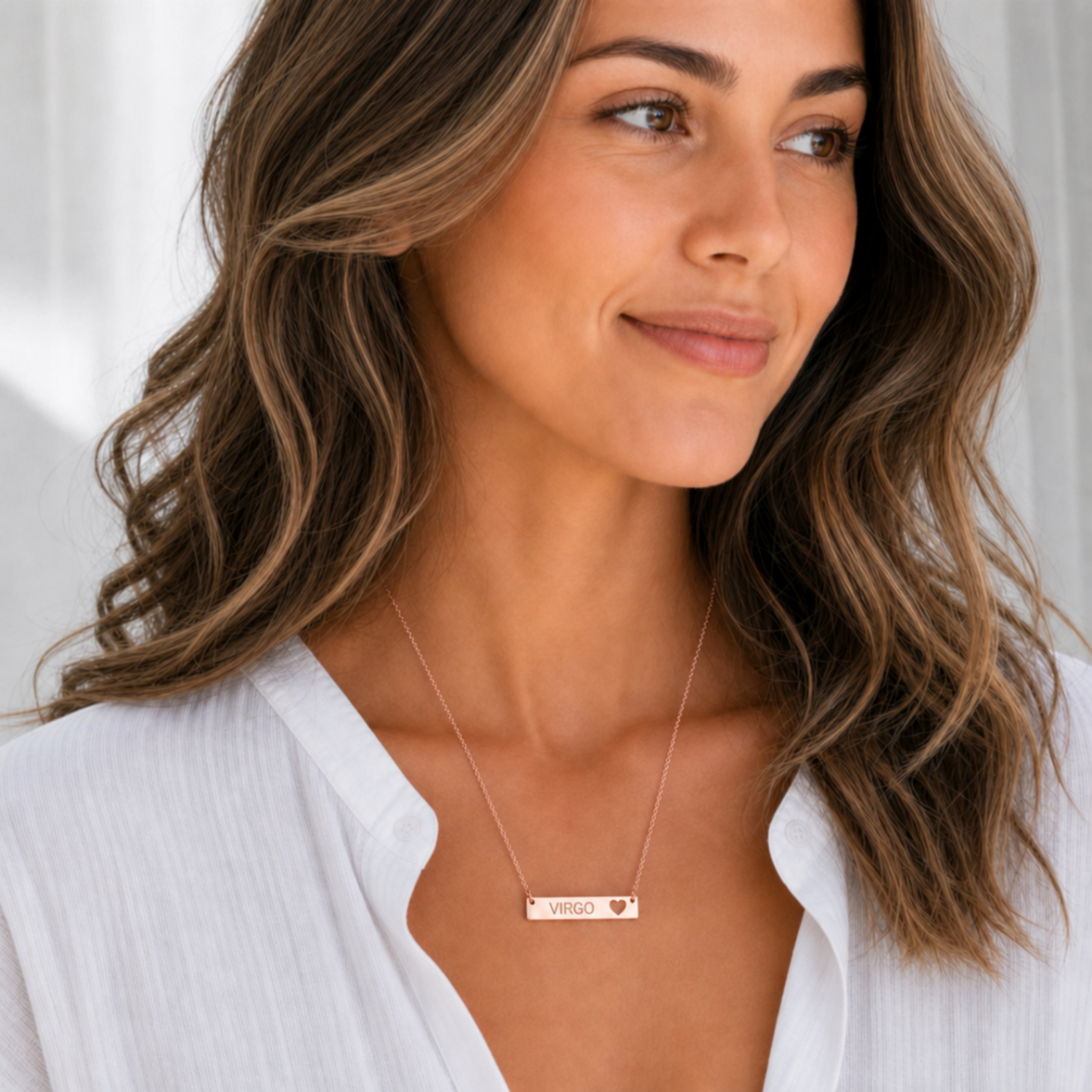 Model wearing the Virgo zodiac necklace in 18K Rose Gold — polished cutout heart bar with grey laser-etched VIRGO, see-through heart cutout, white blouse, bright editorial daylight
