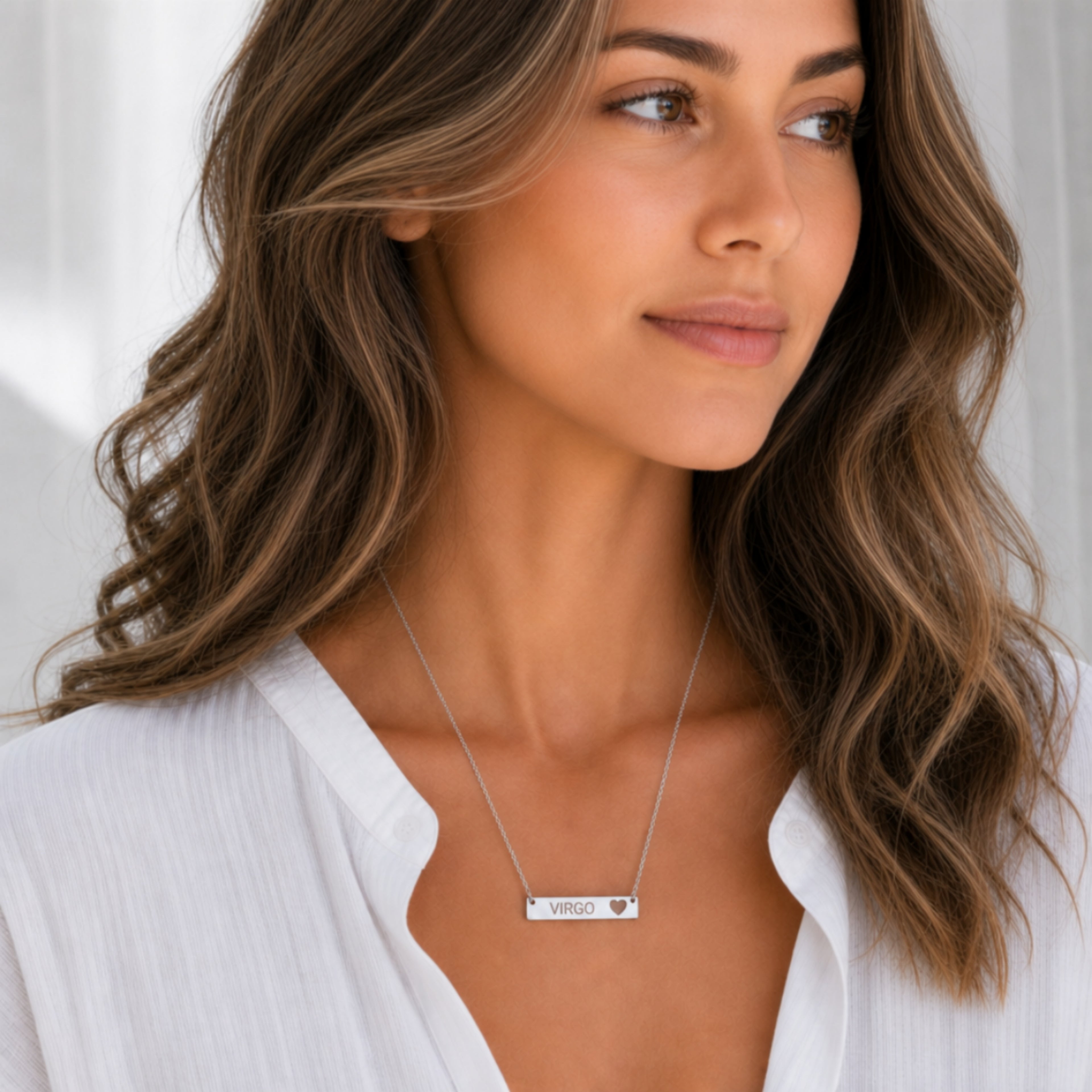 Model wearing the Virgo zodiac necklace in 316L stainless steel — polished mirror cutout heart bar with grey laser-etched VIRGO, see-through heart cutout, white blouse, soft natural daylight