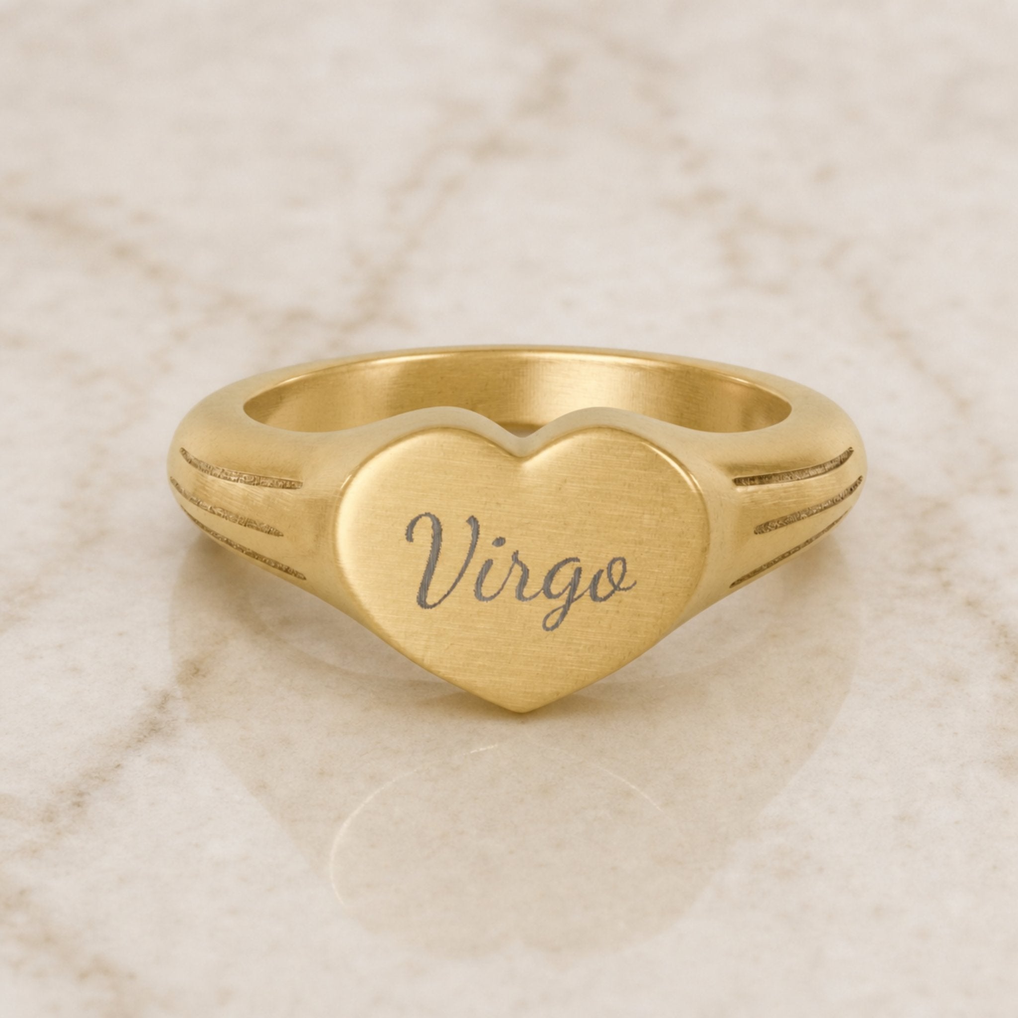 Virgo zodiac heart signet ring — hero macro of laser-engraved Virgo name in Dancing Script cursive on 18K gold heart face