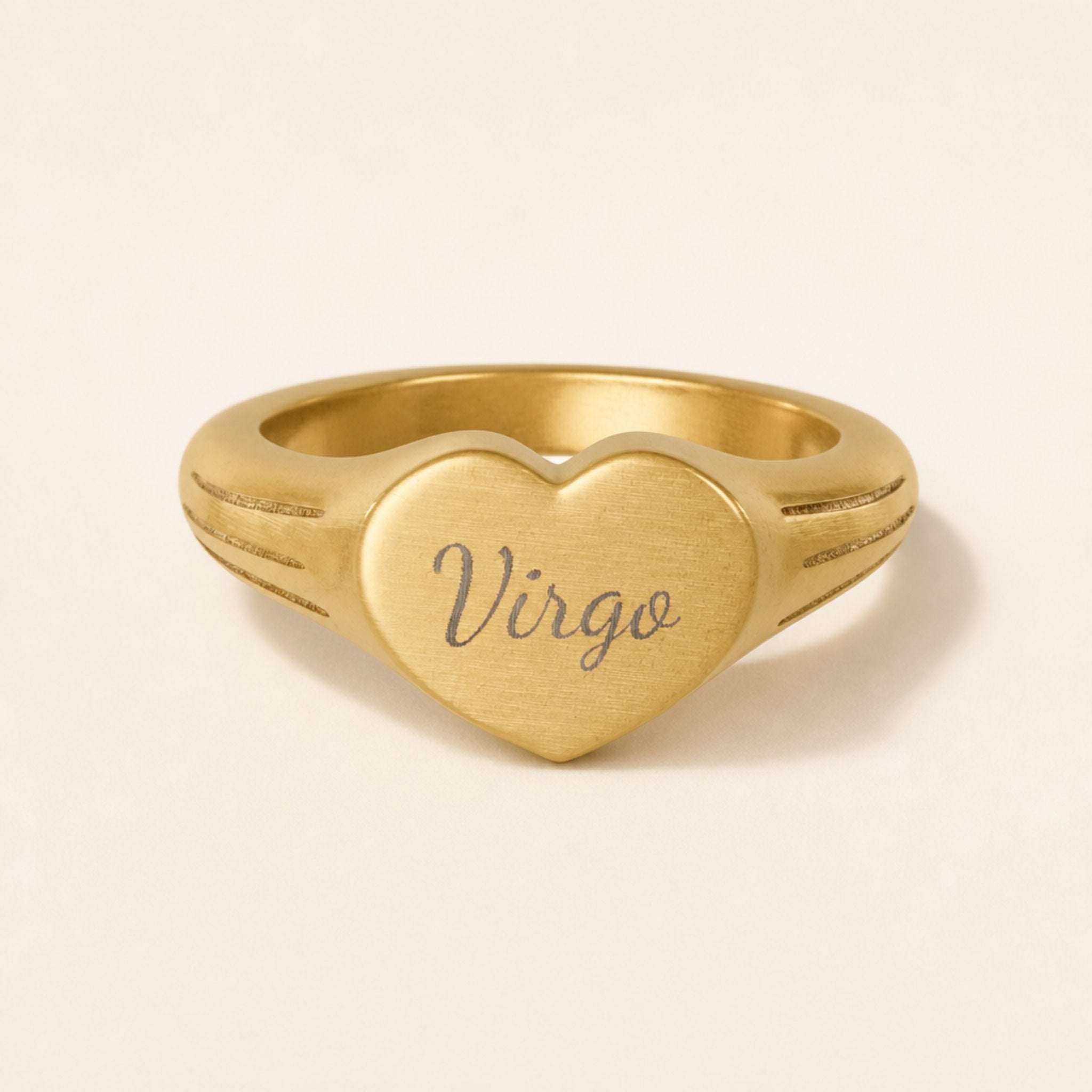 Virgo zodiac heart signet ring studio front — clean cream backdrop product shot, 18K gold matte PVD