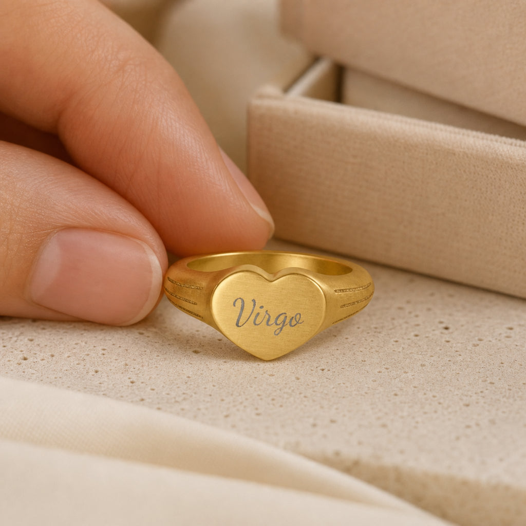 Virgo zodiac heart signet ring scale-in-hand — fingers holding heart ring next to gift box and ruler, dainty signet sizing