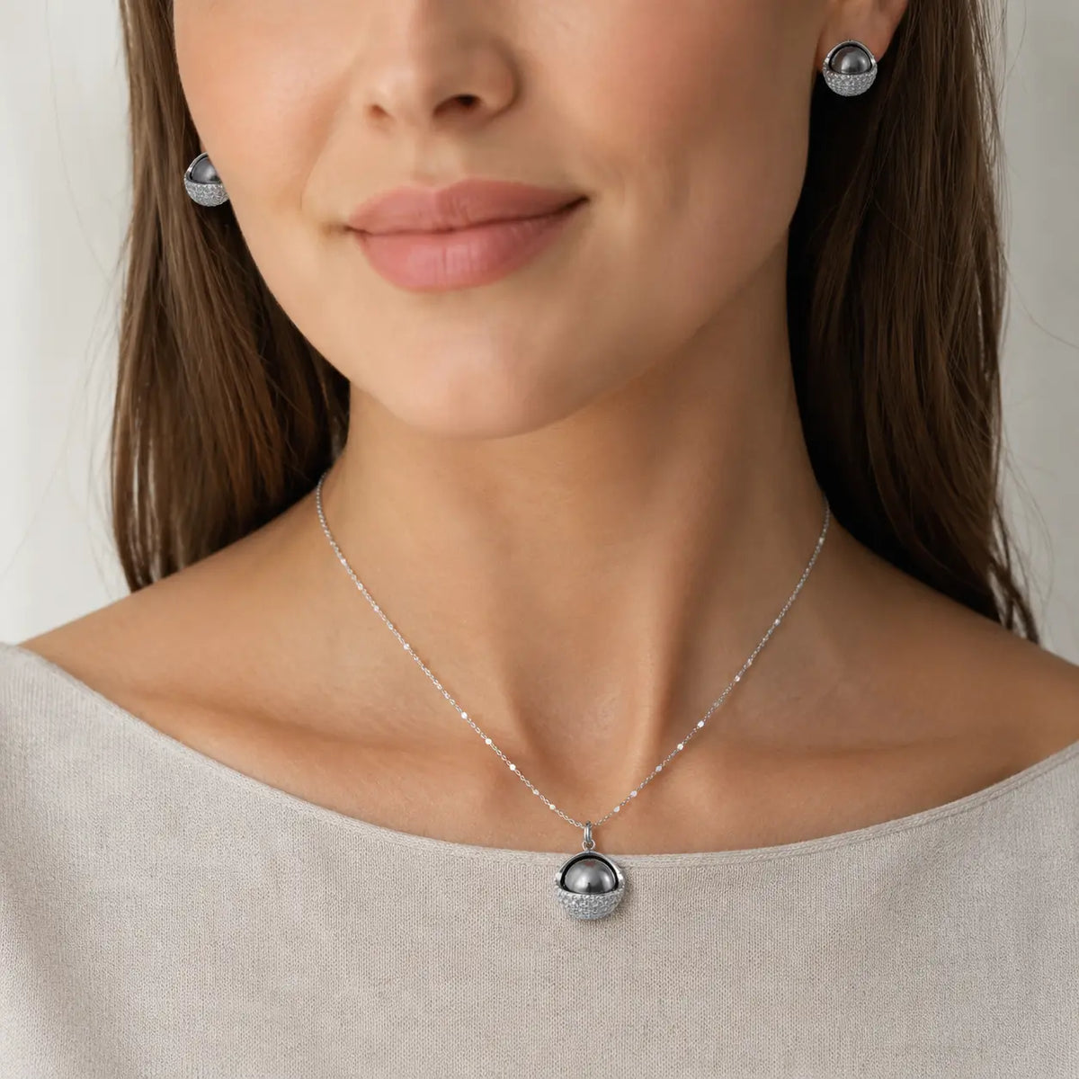 Woman wearing Cosmic Sphere necklace and stud earrings with silver-gray pearl domes