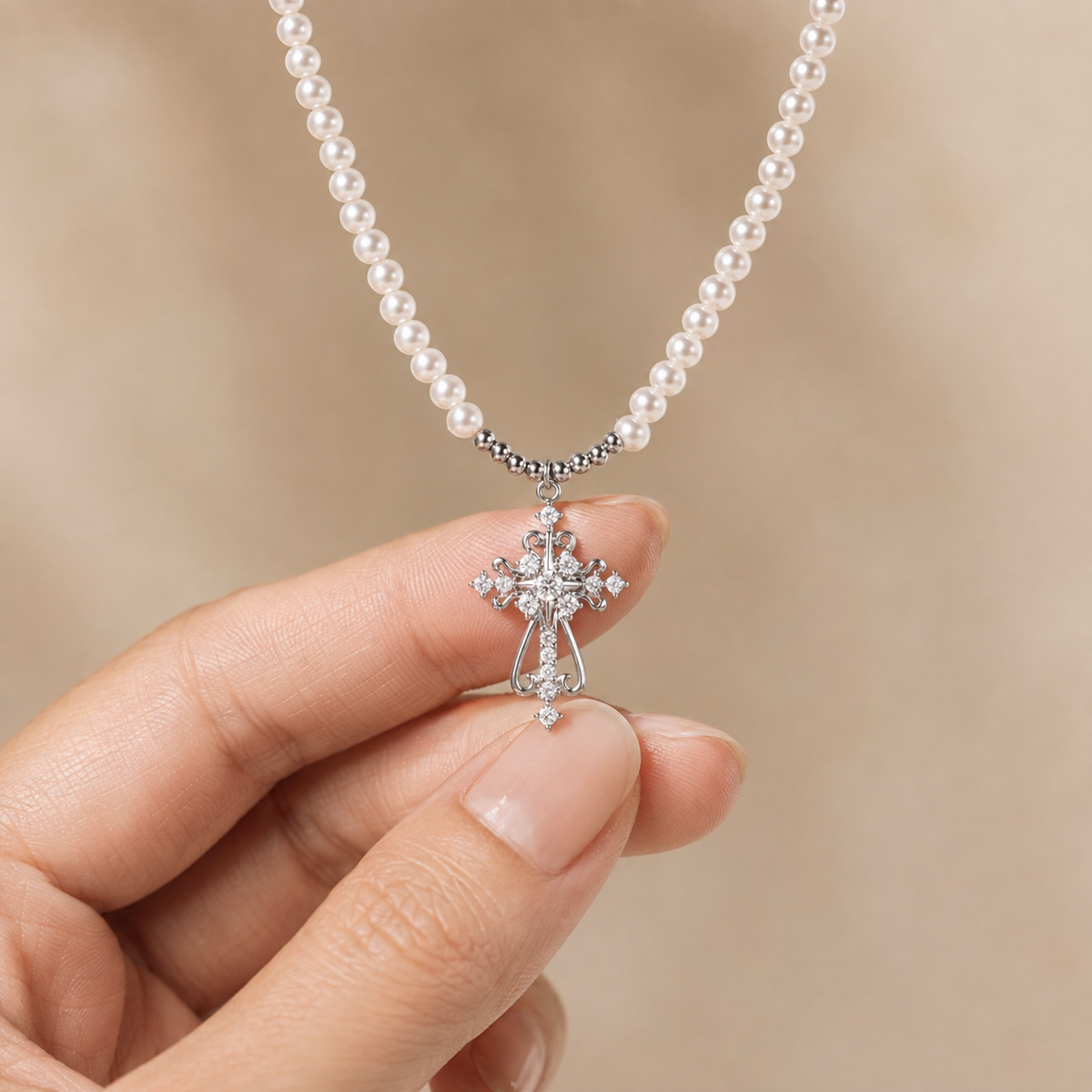 Divine Grace pearl cross necklace held between fingertips to show the petite pendant scale