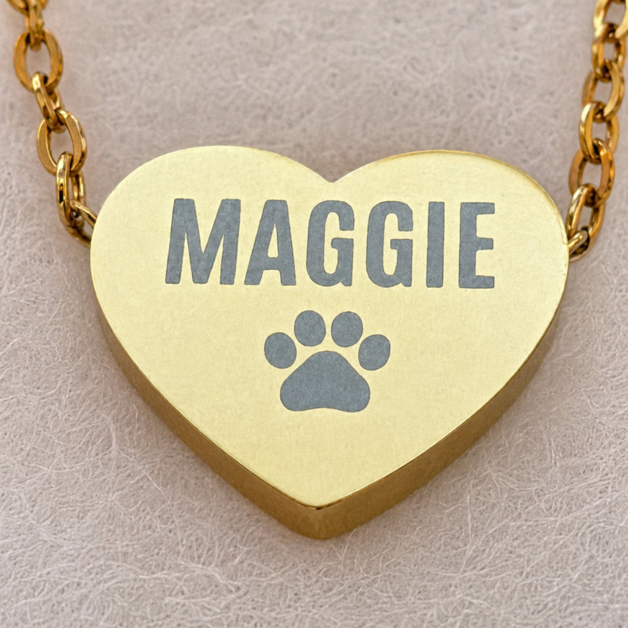 Macro close-up of engraved name and paw print on gold heart pendant — engraving quality detail