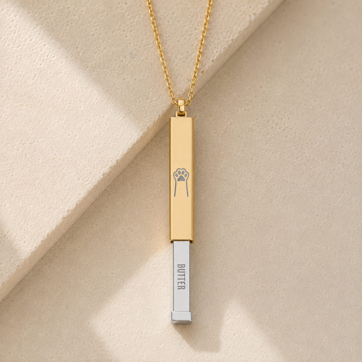 Gold hidden-message slider bar necklace, vertical bar engraved with a paw that slides up to reveal a hidden name - a piece to carry close. Memory That Lasts.