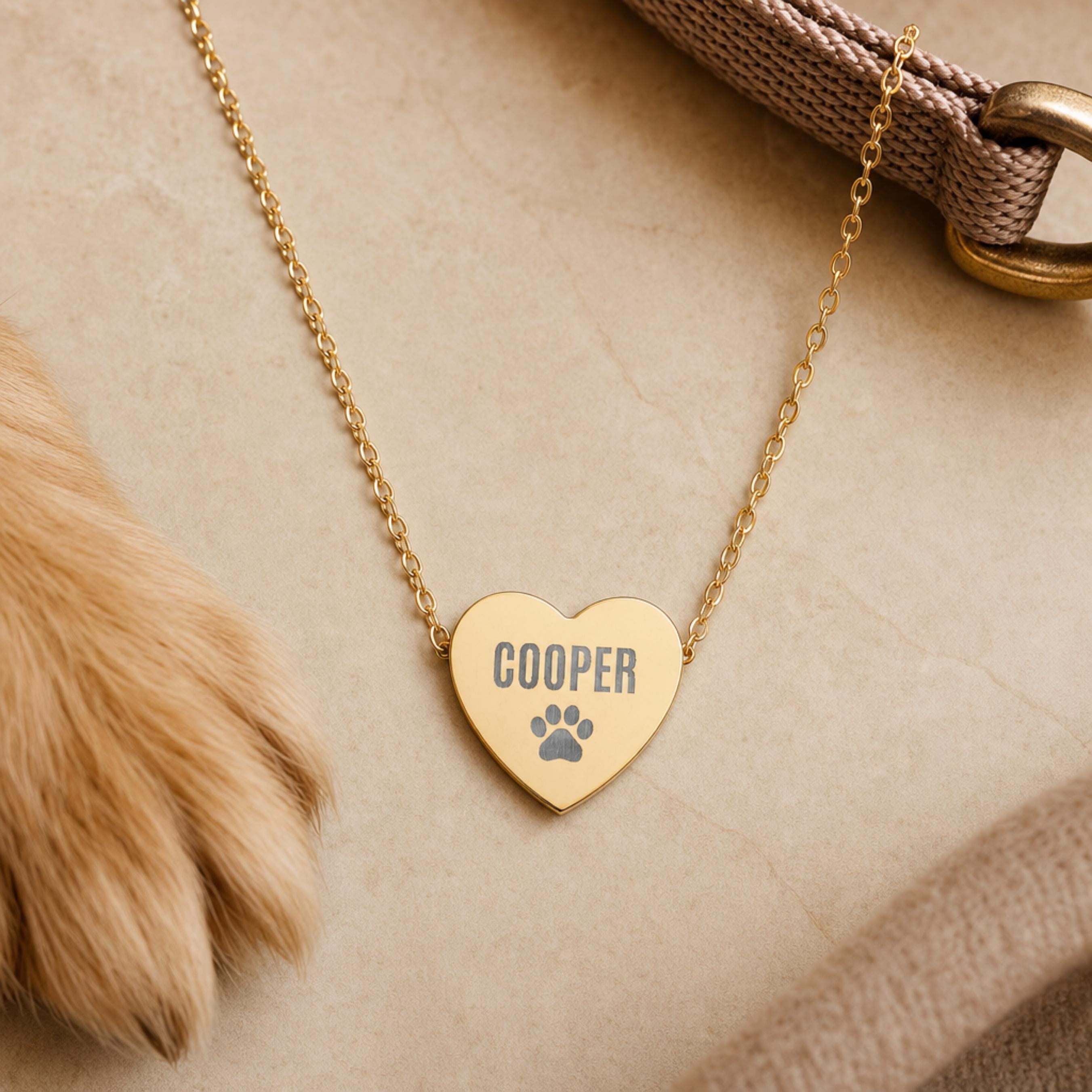 Gold engraved pet name heart necklace styled with a dog paw and collar