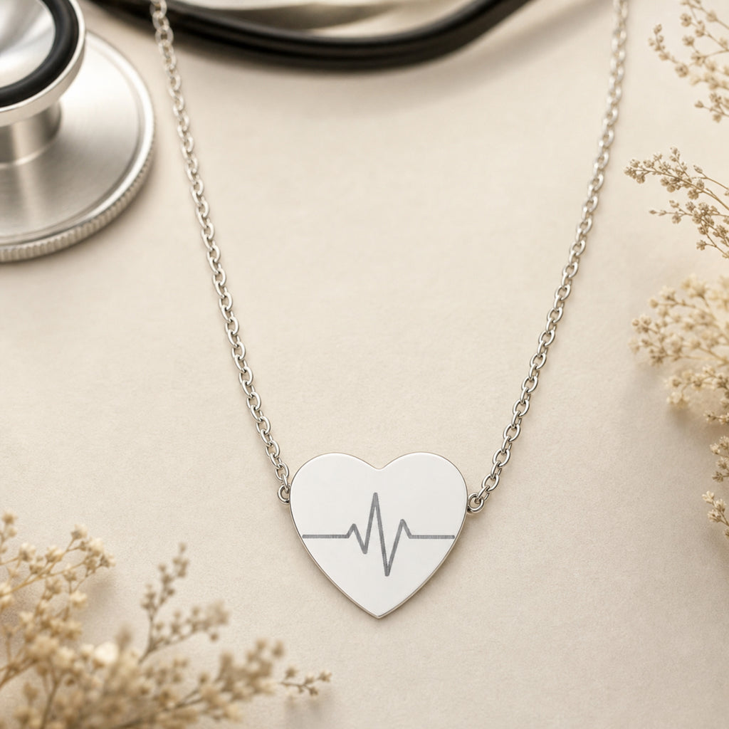 Heartbeat necklace flatlay — stainless steel EKG heart pendant on natural surface. Memory That Lasts.