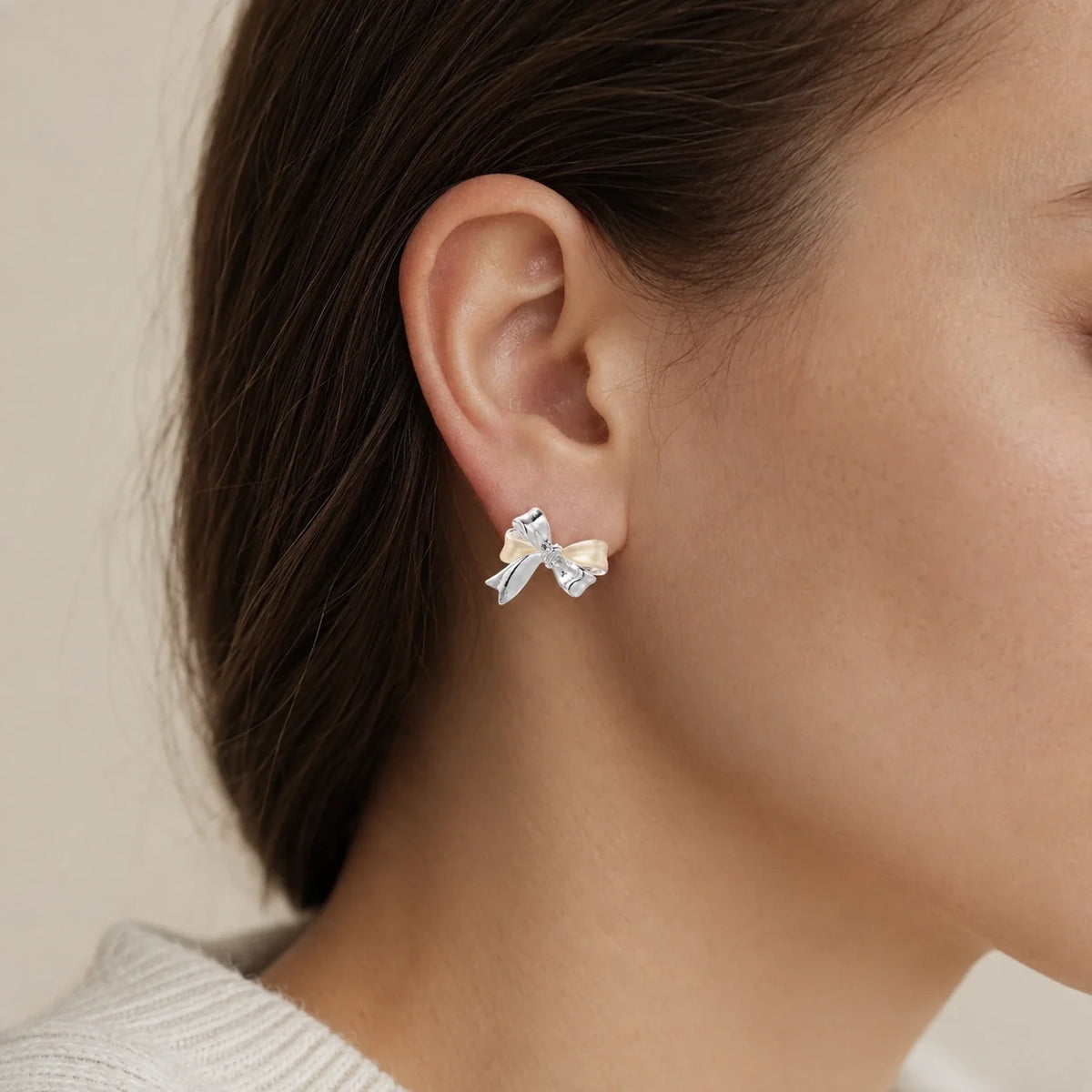 Close-up of a woman wearing a two-tone Pearl Bow Stud with polished silver-tone and cream ribbon details