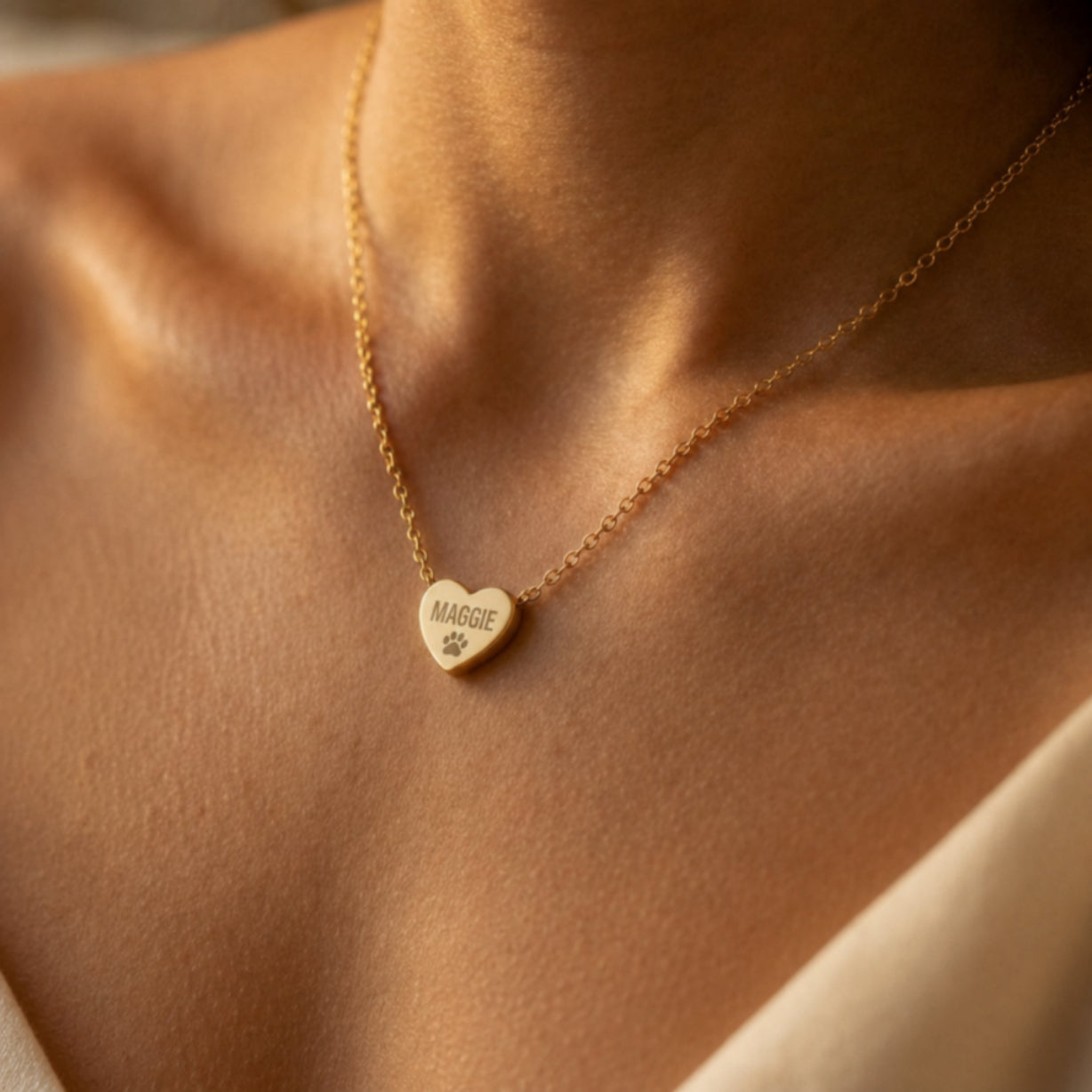 Personalized gold heart necklace engraved with name and paw print, worn on collarbone